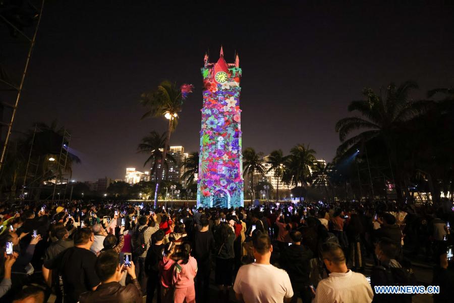 People watch a light show around a bell tower in Haikou, south China