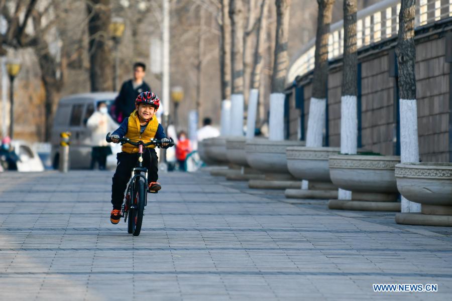 A child rides a bike along the footpath along the Haihe River in Tianjin, north China, Feb. 27, 2021. (Photo by Sun Fanyue/Xinhua) 