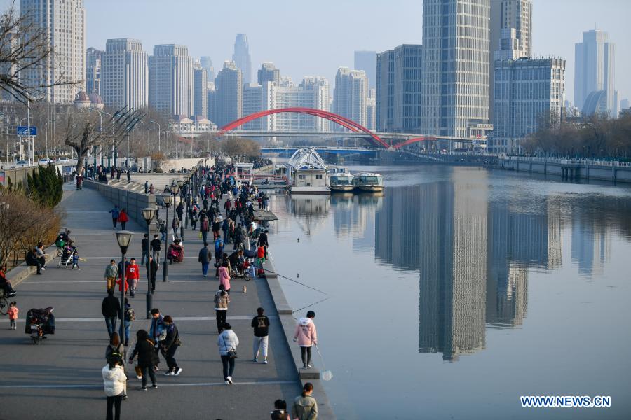 People walk along the footpath along the Haihe River in Tianjin, north China, Feb. 27, 2021. (Photo by Sun Fanyue/Xinhua) 