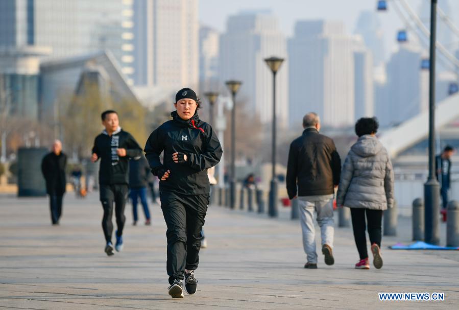 A woman jogs along the footpath along the Haihe River in Tianjin, north China, Feb. 27, 2021. (Photo by Sun Fanyue/Xinhua) 