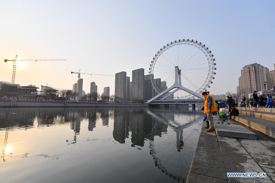 People spend time beside the Haihe River in Tianjin, north China, Feb. 27, 2021. (Photo by Sun Fanyue/Xinhua) 