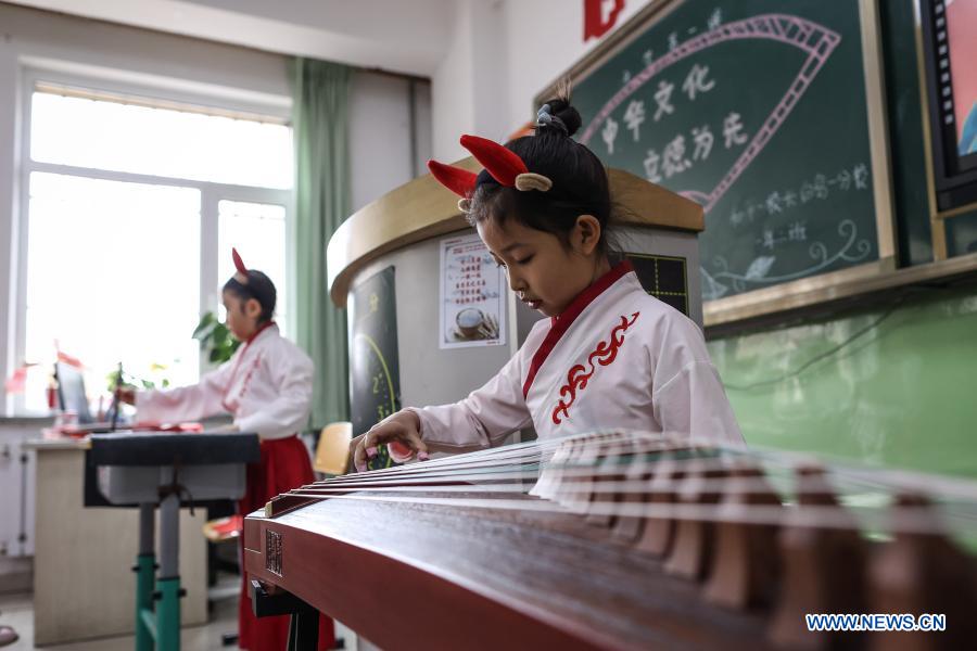 Primary students wearing traditional costumes and ox-themed headpieces perform in class on their first day of the new semester at a primary school in Shenyang, northeast China