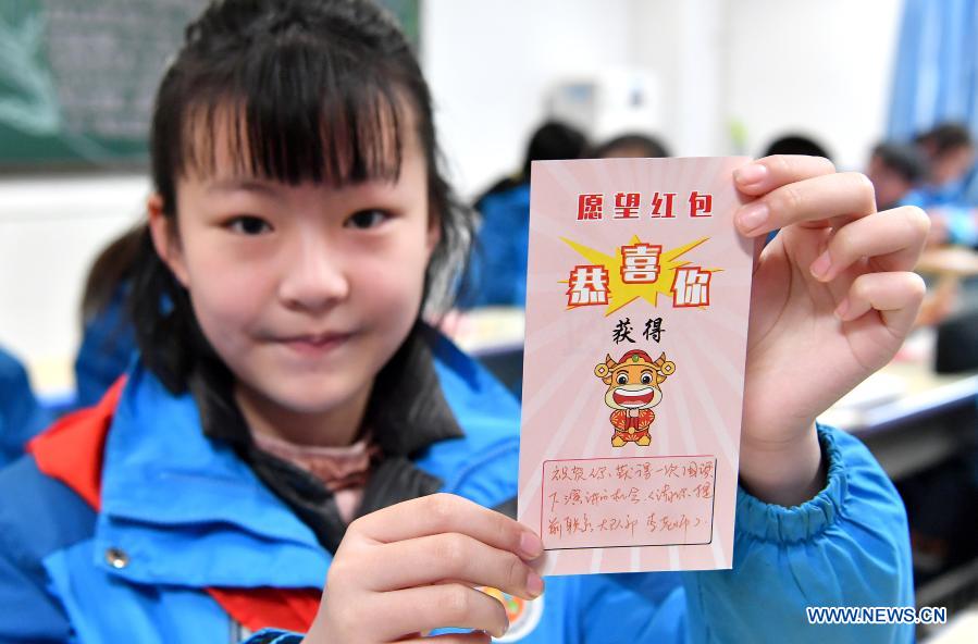 A student shows a wish card she has received congratulating her on getting a chance to deliver a public speech at the national flag raising ceremony at the Experimental Primary School in Beilin District of Xi
