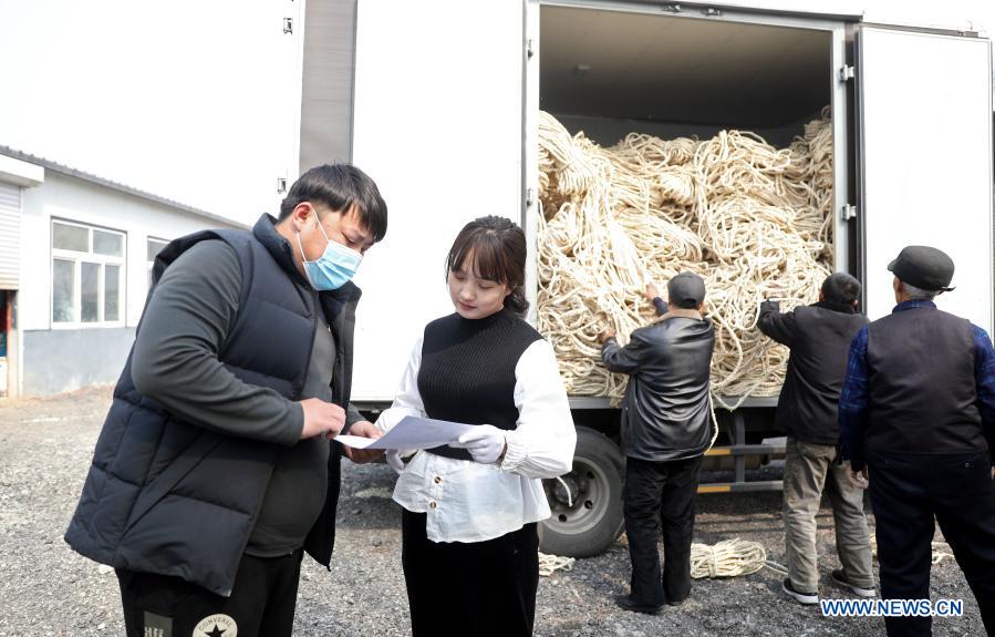 Yan Jiaxin (2nd L) handles invoices with a material delivery worker in Qiaotuo Village of Tai