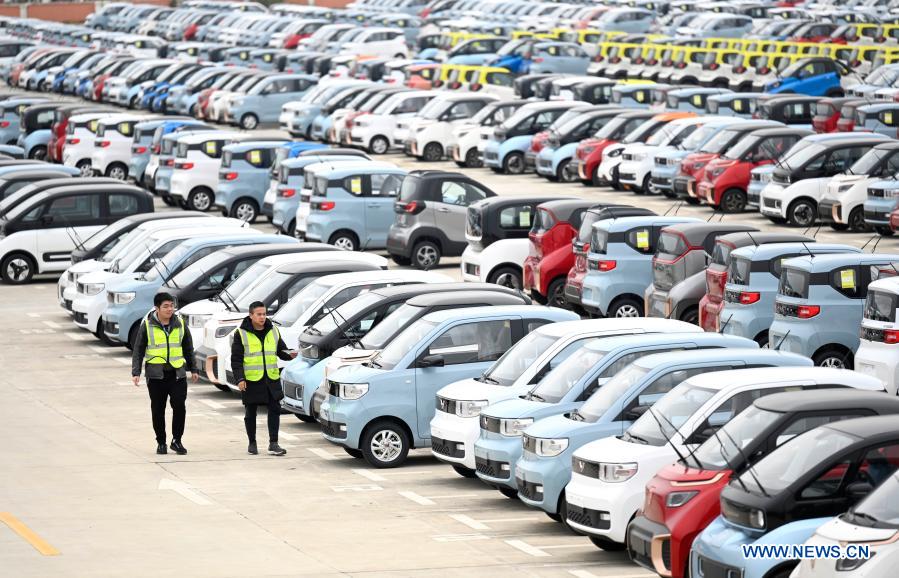 Workers check new energy vehicles at a logistics park in Liuzhou, south China