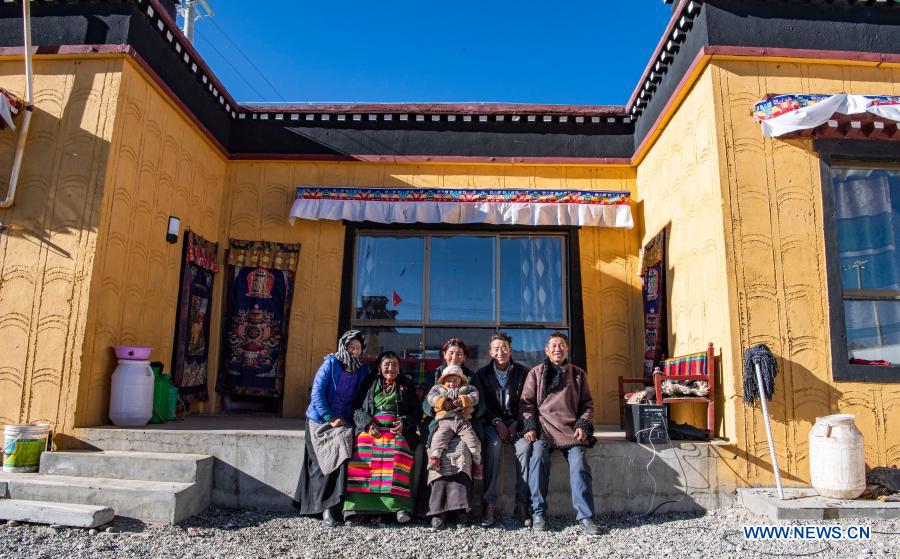 Tenzin Tsomo poses for a photo with her family members in front of their new house in southwest China