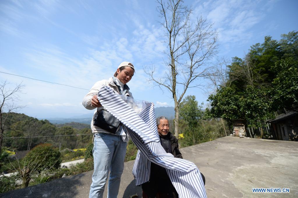 Zhuo Yihang prepares to give haircut to an elderly person in Liangshan Village in Cili County, central China