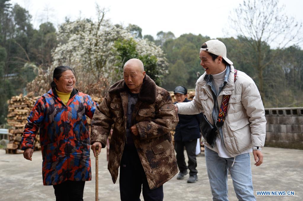 Zhuo Yihang (R) talks with an elderly person in Liangshan Village in Cili County, central China