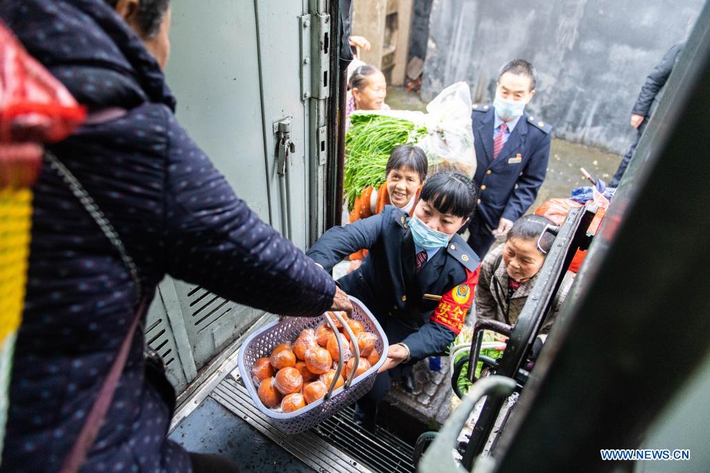 A conductor helps passengers board the train 7266 at Mayang Station in central China